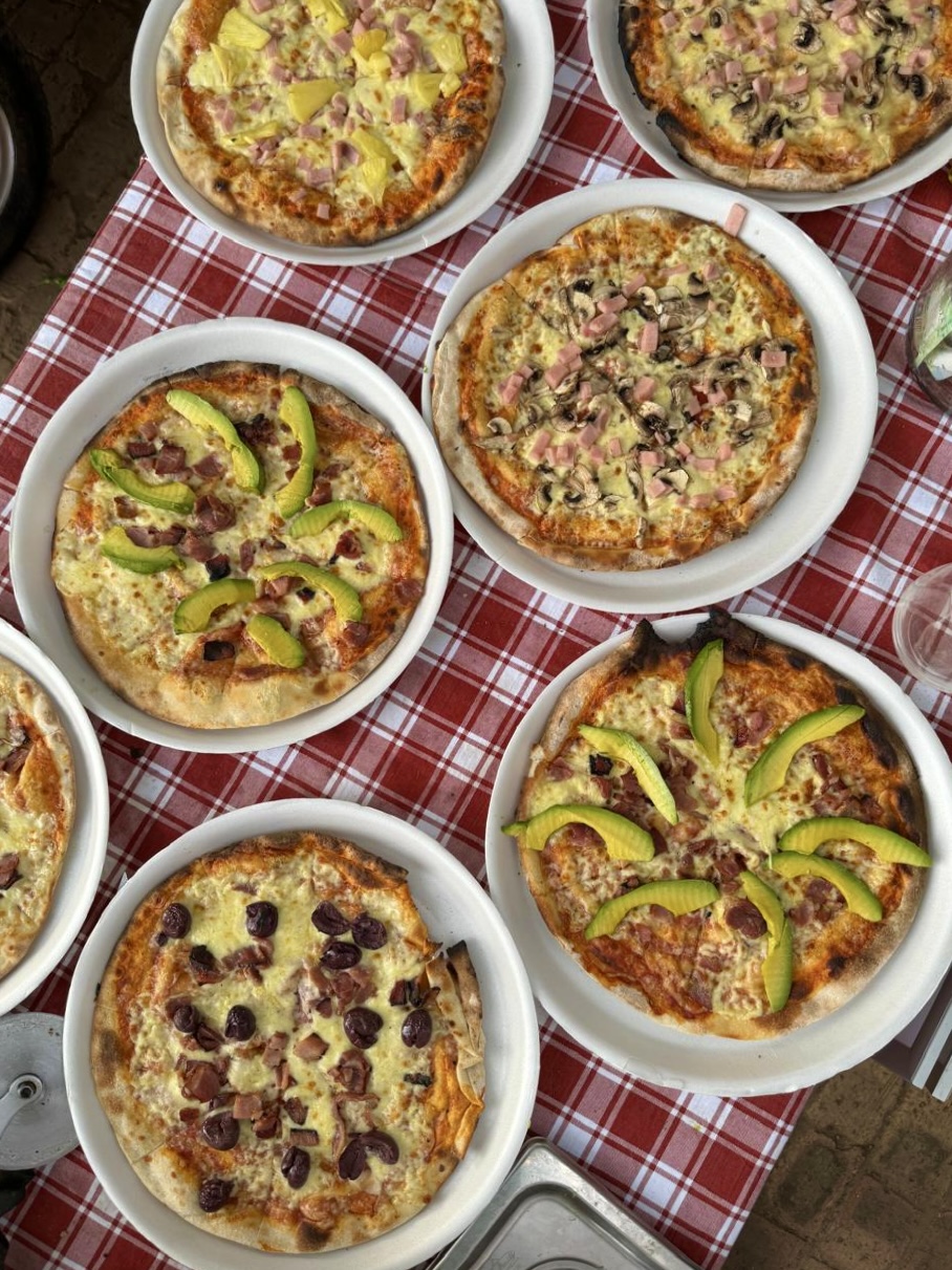 A spread of wood-fired pizzas on a classic red checkered tablecloth
