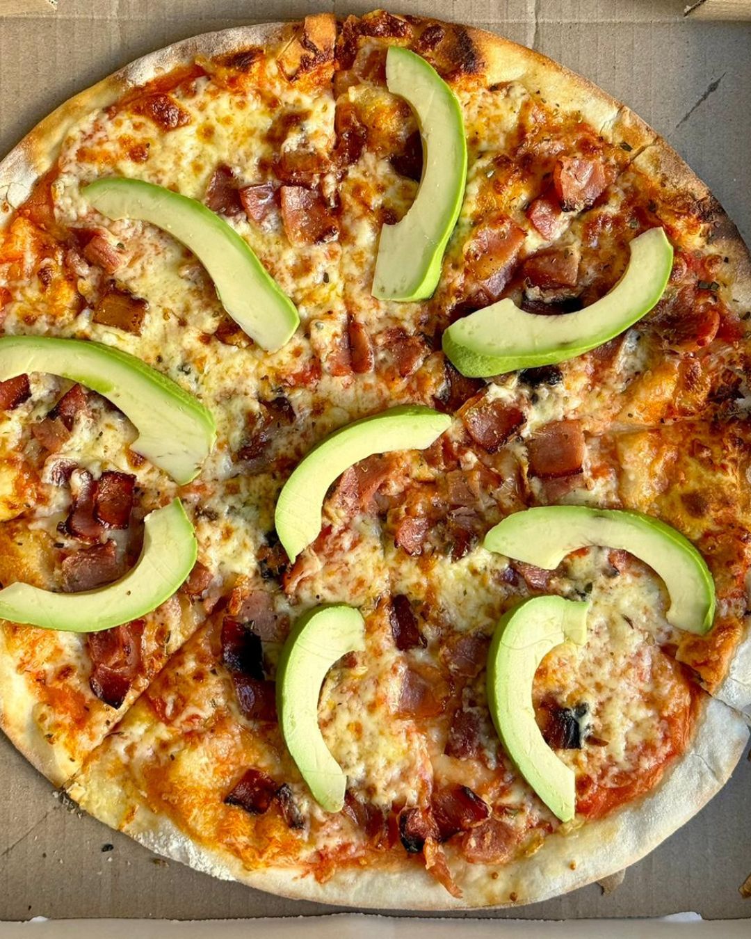 Bacon and avocado wood-fired pizza fresh in the box