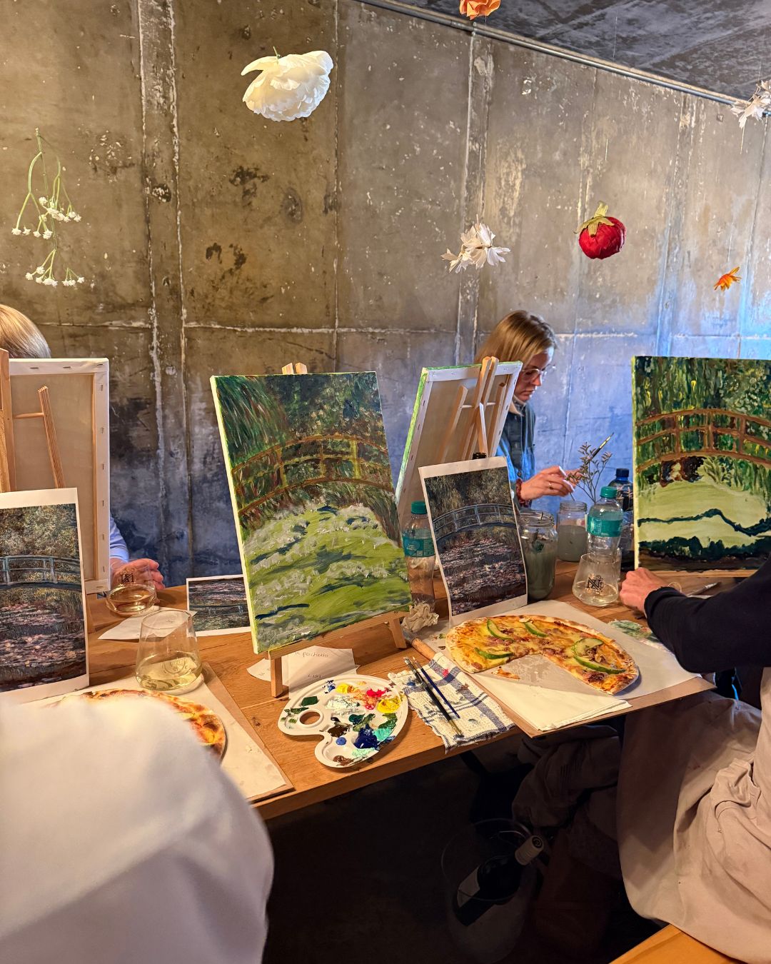 A paint-and-pizza evening with canvases, wine and fresh pizzas on the table